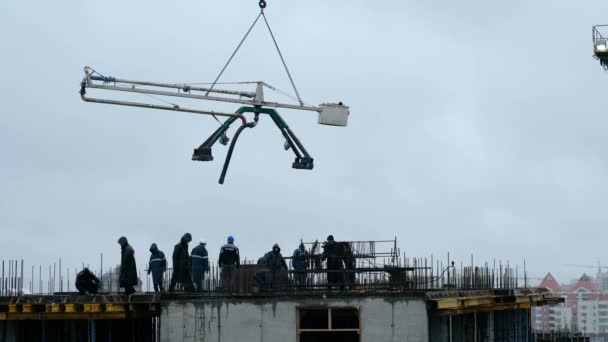 Trabajadores de la construcción vertiendo hormigón húmedo utilizando manguera de araña de hormigón o trabajo de bomba en el sitio de gran altura. trabajo bajo la lluvia — Vídeos de Stock