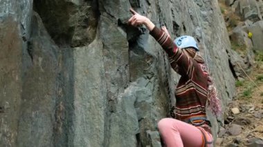 Kadın tırmanışçı kayanın üzerinde zorlu yolları geçer.