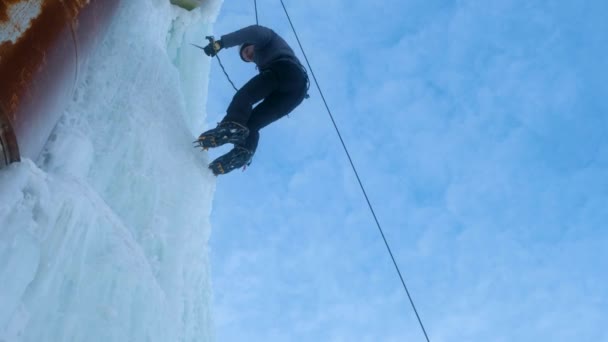 Hombre alpinista con hacha de herramientas de hielo escalando una gran pared de hielo. bajando en cuerda — Vídeos de Stock