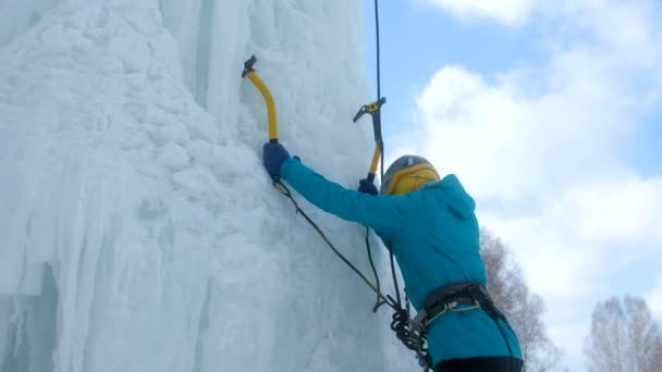 Alpinist kvinna med is verktyg yxa och kramper klättring vägg av is. — Stockvideo