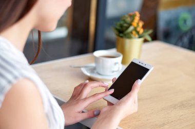 Akıllı telefon ve bir fincan kahveyle iş kadını elleri. Grafik görüntüleme montajı için.