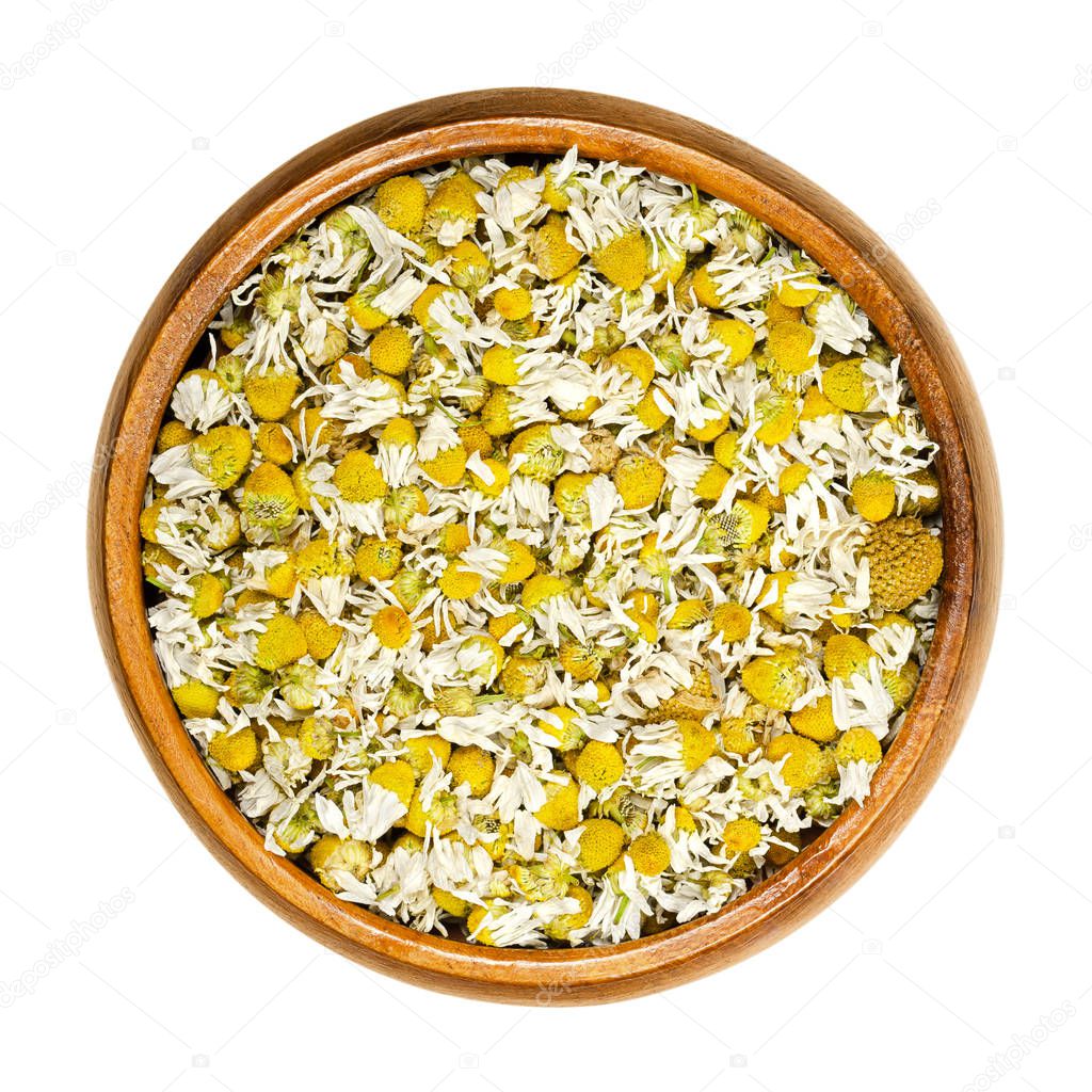 Dried chamomile blossoms, camomile tea in wooden bowl