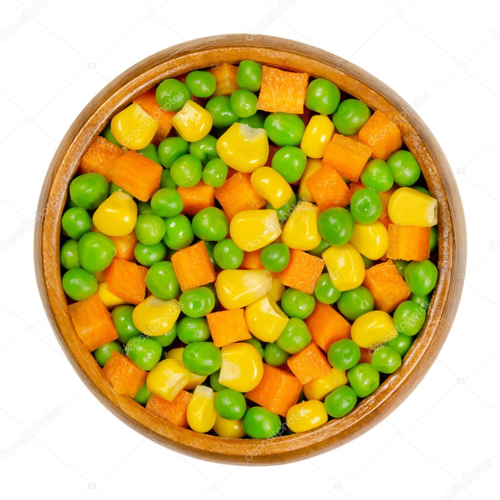 Green peas, corn and carrot cubes in wooden bowl. Mixed vegetables. Peas mixed with  vegetable maize, also called sugar or pole corn and with carrots cut in cubes. Closeup from above macro food photo.