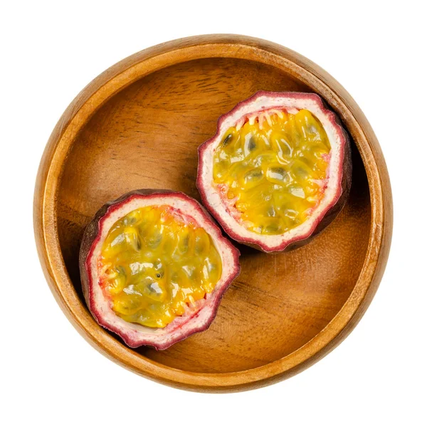 新鮮な情熱の果物の2つの半分で 木製のボウルにカット 紫色の肌と多くの種子を持つ黄色の肉を持つ果物 生で食べることができます ジュースや香りを強化するために使用 住血吸虫症 クローズアップ写真 — ストック写真