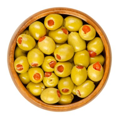 Tahta bir kasede kırmızı tatlı biberle doldurulmuş küçük yeşil zeytin turşusu. Doldurulmuş dolma biberli Olea Avrupa meyveleri. Yukarıdan yakın çekim, beyaz arkaplanda izole edilmiş, makro yiyecek fotoğrafı.