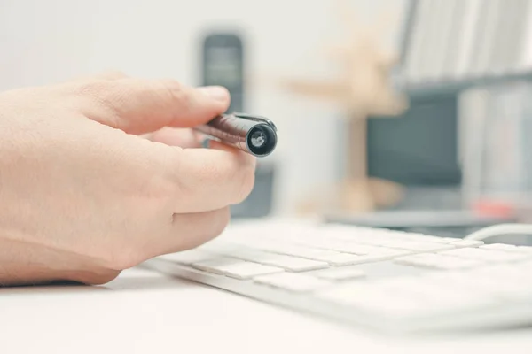 Homem escritório trabalhador segurando caneta enquanto trabalhava no computador desktop . — Fotografia de Stock