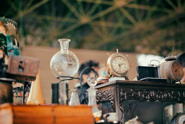 Bit pazarında eski moda saatler, vazo, abajur ve komodin. Antika pazarının tezgahında eski mobilyalar.