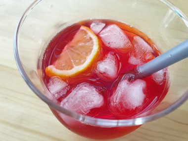 Tahta masada limon ve buzla dolu cam bir fincanda ferahlatıcı antioksidan amber çayı. Yazın tazelik.