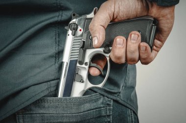 Adam Jean 'in cebinden otomatik silahını çıkarıyor. Gizli tabanca konsepti.