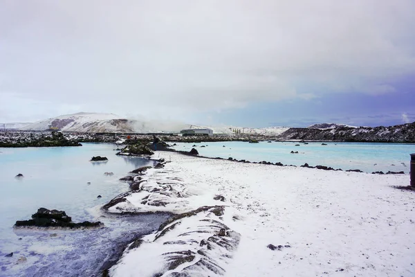 Геотермальная зона голубой лагуны с голубой и молочной водой, покрытые снегом горы и электростанция — стоковое фото
