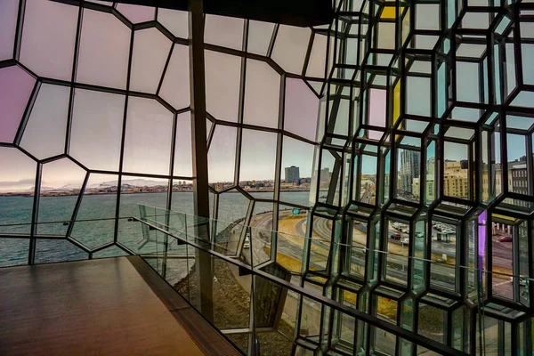 Вид через скляний фасад Harpa, з містом Рейк'явік у фоновому режимі Стокове Зображення