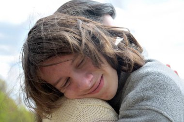 Genç ve güzel bir kadın. Anne, genç oğlunu okşayıp kucaklıyor.