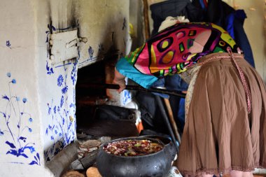 geleneksel giysiler içinde kırsal kadın ateşe bir tencere koyarak bir 