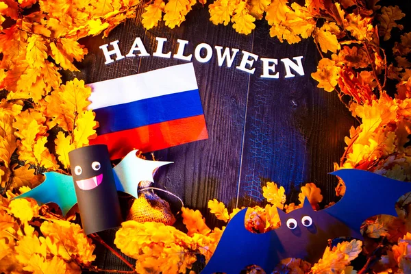 Halloween in Russia. Russian flag and the inscription Halloween. Flag of Russia surrounded with yellow oak leaves. Toy bats.