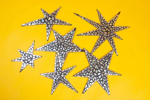 Brilliant stars. Stars from pieces of a mirror. Mirror stars on a yellow background.