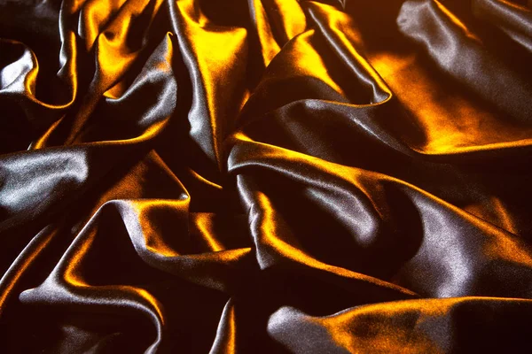 Black silk. Fabric of black silk with golden tint. Background of black silk.