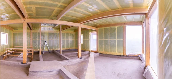 The frame of the house. The frame of the cottage with the warming of the walls. Panorama of the construction site. Walls of a house under construction. Warming of the walls of the building.