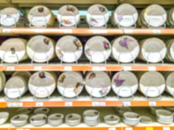 Blurred background. Shelves with goods. Household products. goods for the kitchen. Sale of plates. Score. Hypermarket. Dishes. White dishes on the shelves.