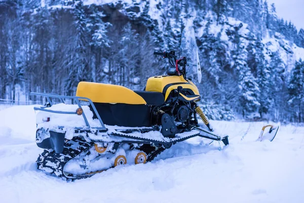 Yellow Snowmobile. Snowmobile on the background of the mountain.