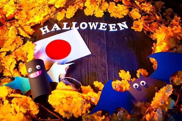Japanese flag and the inscription Halloween. Halloween in Japan. Toy bats. Flag of  Japan surrounded with yellow oak leaves.
