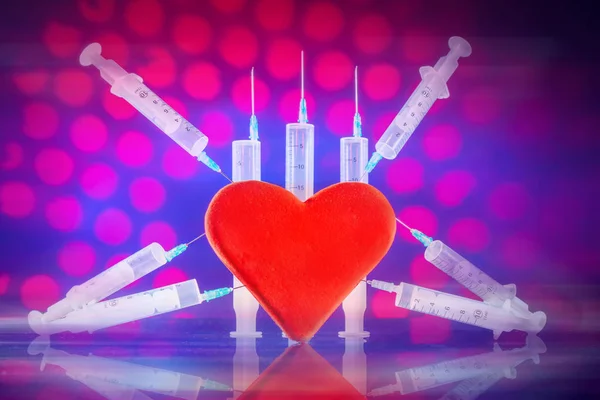 Red heart punctured with syringes. Diseases of the heart. Treatment with injections. Application of syringes in medicine.