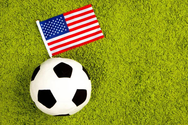 Soccer ball with the flag of the United States of America. Football in the USA. Soccer ball on a green lawn. Flag of the USA.
