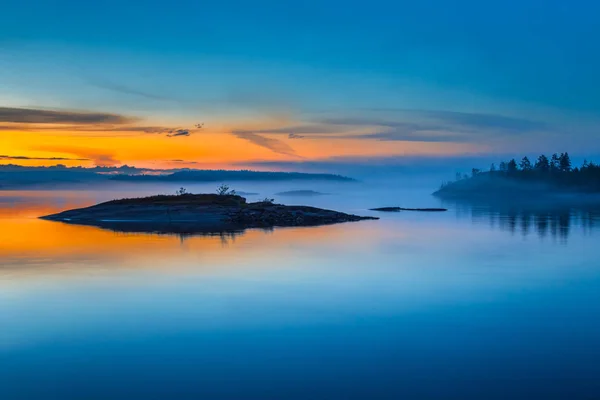 Fog over Lake. Sunrise in the fog. Wild nature of Finland. Islands of stone. Mirror reflection in water. Summer in Finland.