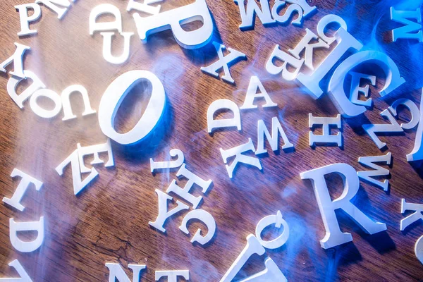 Letters of the Latin alphabet on the table. White Latin letters. Latin alphabet in smoke.