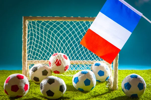 Team of France in football. Flag of France at the football stadium. The symbol of France. The flag of France hangs on the background of the goalie gate. Colored soccer balls.
