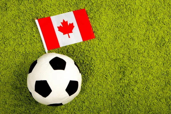 Soccer ball with the flag of Canada. Football in Canada. Soccer ball on a green lawn. Flag of Canada.