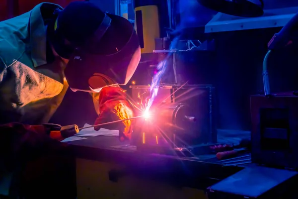 Welding work. A man in a protective mask. Welder. Welding work in production. Sparks from welding. A man welds metal products.