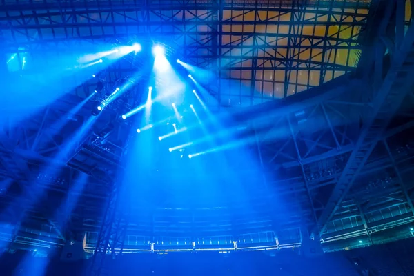 Spotlights shine blue. Light guns. Spotlights on a metal tower. Stadium lighting. Concert equipment.
