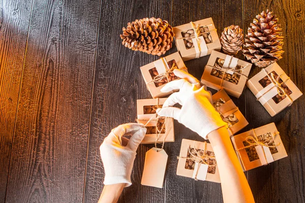 Hands in white gloves are packing nuts. Nuts trading. Boxes with nuts and cones on a brown background. Almonds, cashews, walnuts and pine nuts. Packing in boxes