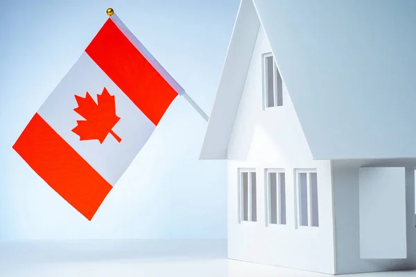 White cottage with flag. House with the flag of Canada. Immigrat