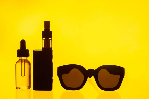 The concept of vaping. Accessories for vaping on a yellow background. Place for inscription. Smoking e-cigarettes. Gadgets vaper. VAPE shop. Liquid for electronic cigarettes. Fashion devices.