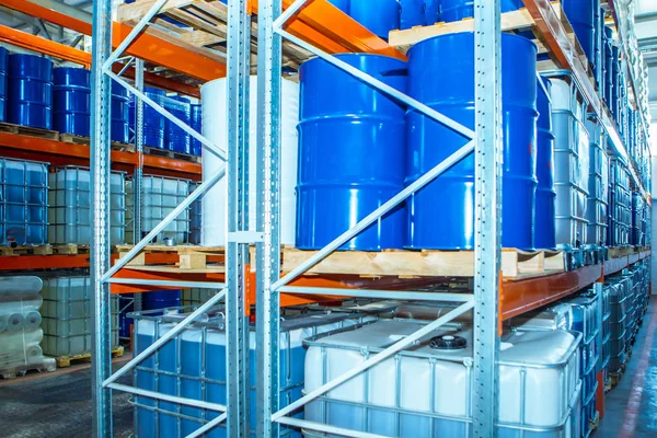 Chemical liquids in barrels are stored in the warehouse. Barrels and containers on pallets are on the shelves. Chemical production warehouse. Chemical industry. Fuel storage.
