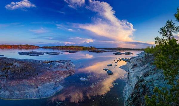 Russia. Panorama Of Karelia. Skerries of lake Ladoga. Northern nature. Evening in Karelia. Rocky Islands and pine trees. Sunset on lake Ladoga. Stones protrude from the water. — Stock Image Russia. Panorama Of Karelia. Skerries of lake Ladoga. Northern nature. Evening in Karelia. Rocky Islands and pine trees. Sunset on lake Ladoga. Stones protrude from the water. Stock Photo