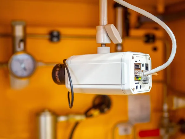 White camera in the shop of an industrial enterprise. Camera to record the process of production. Remote monitoring of the conveyor. Control of equipment operation by means of a video camera.