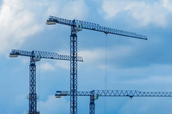 Tower cranes against the blue sky. The concept of the construction. Cranes for construction of high-rise buildings. Urban construction. Urban development. Urban architecture.