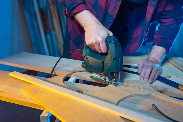 Joiner. The master works with an electric jigsaw. Cutting a piec