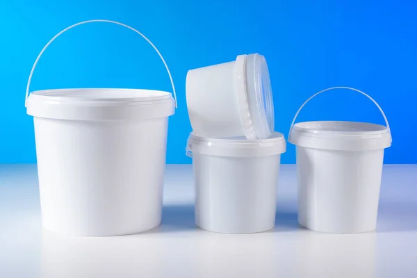 Plastic buckets. Jar with a handle for storing food. Container for food production. Plastic buckets without labels. White buckets are on the table. Plastic cans with pen. Food Packaging.