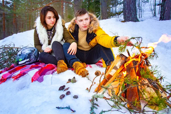Gatherings by the fire at Christmas.A guy and a girl by the balefire.A loving couple kindles a fire.People around the winter bonfire. Picnic in the winter forest.A man and a woman are sitting in the s