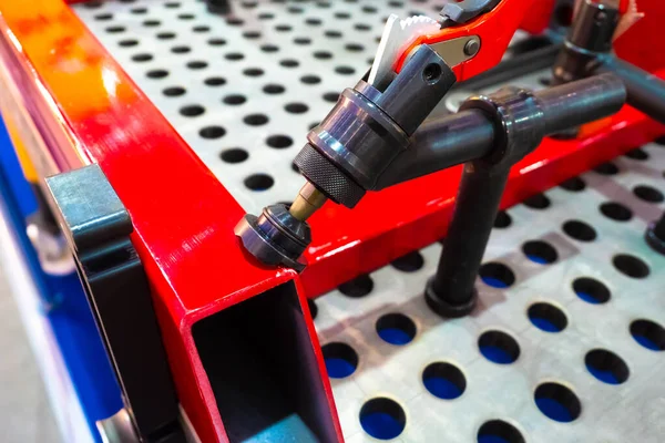 Clip for fixing metal parts on the mounting table. Fixation of the welded metal product on a special frame. Powerful red clamp.