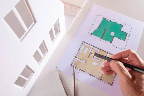 The architect makes pencil marks on the plan of the future house.Adjustment of the construction plan. Engineer checks the drawing of the building. Preparation of documents for the cottage construction