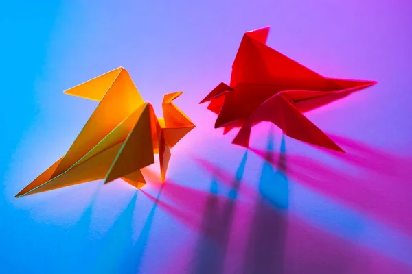 Metaphor is an equal battle. Concept - a conflict of interest. Fight for customers in business. Competitors in business. Look into the eyes of your fears. Origami from colored paper. Miniature dragons