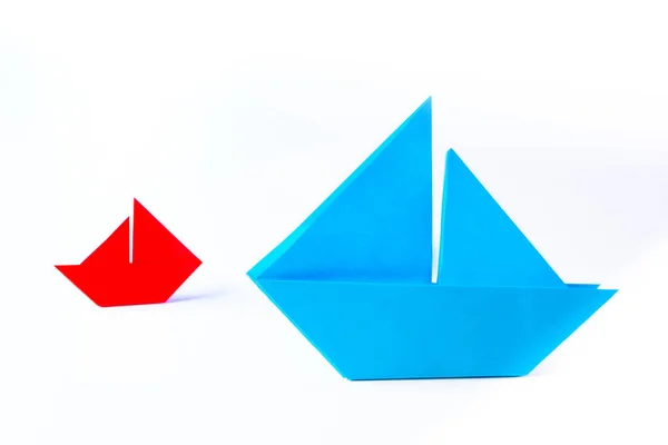 Origami. Two paper boats on a white background. From small grows large. Large and small business. Small things can get big. The pursuit of success, regardless of size.