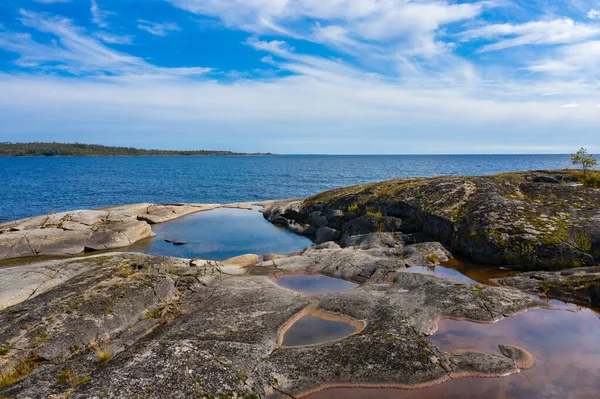 Karelia. Russia. Karelia against the blue sky. Ladoga. The nature of Karelia. Panorama of Lake Ladoga. Northern nature. Untouched nature in Russia. The stone coast. The rocky coast of Ladoga. — Stock Image Karelia. Russia. Karelia against the blue sky. Ladoga. The nature of Karelia. Panorama of Lake Ladoga. Northern nature. Untouched nature in Russia. The stone coast. The rocky coast of Ladoga. Stock Photo