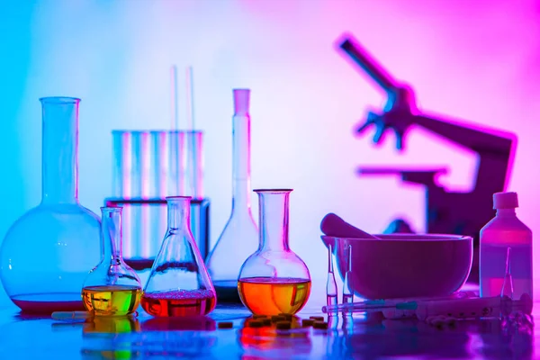 Chemical dishes, reagents and medicines on the table. Laboratory of a pharmaceutical company. The microscope and the solution is to study the composition of the tablets. Chemistry in medicine.