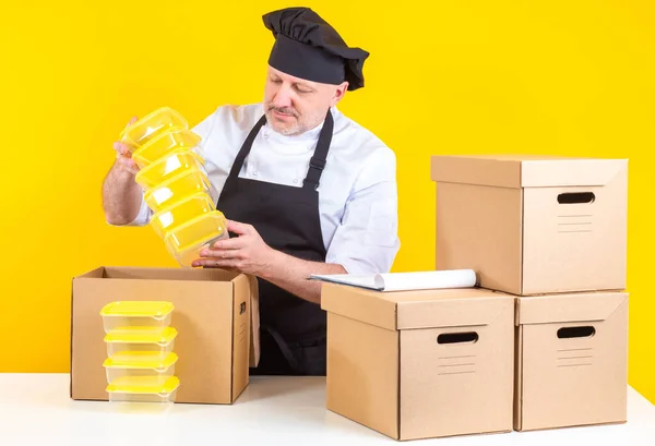 Cook takes out empty containers from box. Restaurant chef holds empty containers. Chef unpacks the boxes. Concept - restaurant relocation. Inventory for cafe. Chef man bought new tableware