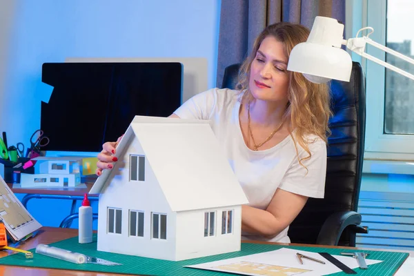 Models of buildings to order. Custom 3d mockup. Create three-dimensional copies. Architectural layout. Designer makes a miniature copy of the house. Girl in the office. Woman at the office